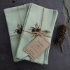 Pair of sage unbleached cotton napkins on slate with bee design