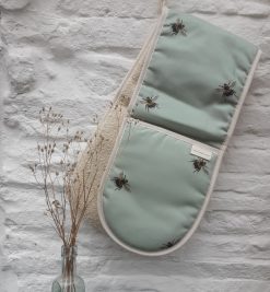 Bee oven gloves hanging on white wall