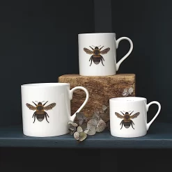 Three Bee mugs with leaves on shelf