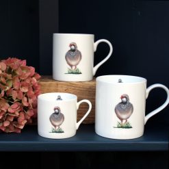 Partridge mugs in three sizes on shelf with flowers