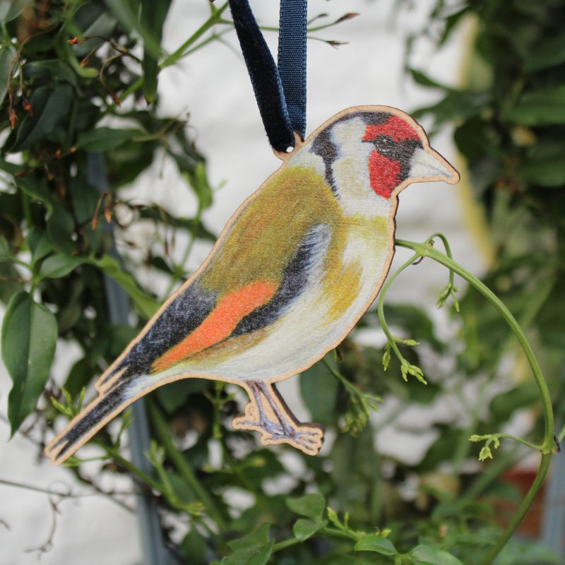 Goldfinch wooden hanging decoration with ribbon hanging on plant